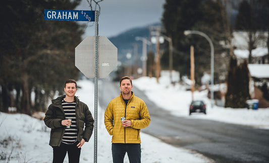 Scott and Kyle from The Graham Avenue podcast stand in front of the Graham Avenue road sign on a winter day in Terrace, British Columbia.